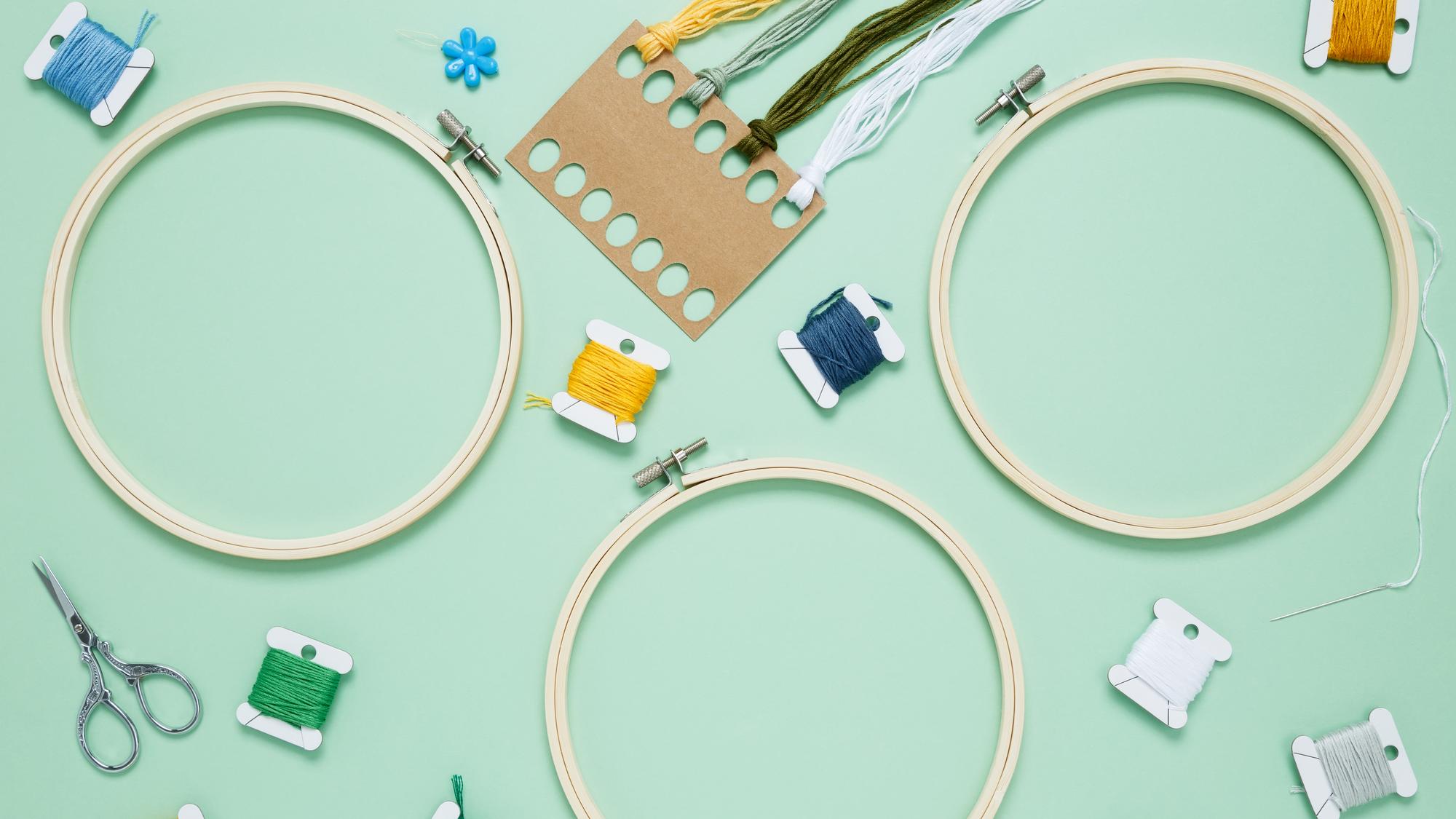 Worktable with threads, hoops, and a finished embroidered patch